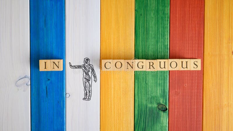 Top view of a hand drawn silhouette of a man pushing away letters IN.from the word Incongruous. Over colorful wooden background. Top view of a hand drawn silhouette of a man pushing away letters IN.from the word Incongruous. Over colorful wooden background