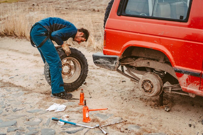 Cambio del hombre la rueda manualmente en un 4x4 del cami?n del camino fotografía de archivo Cambio del hombre la rueda manualmente en un 4x4 del cami?n del camino fotografía de archivo