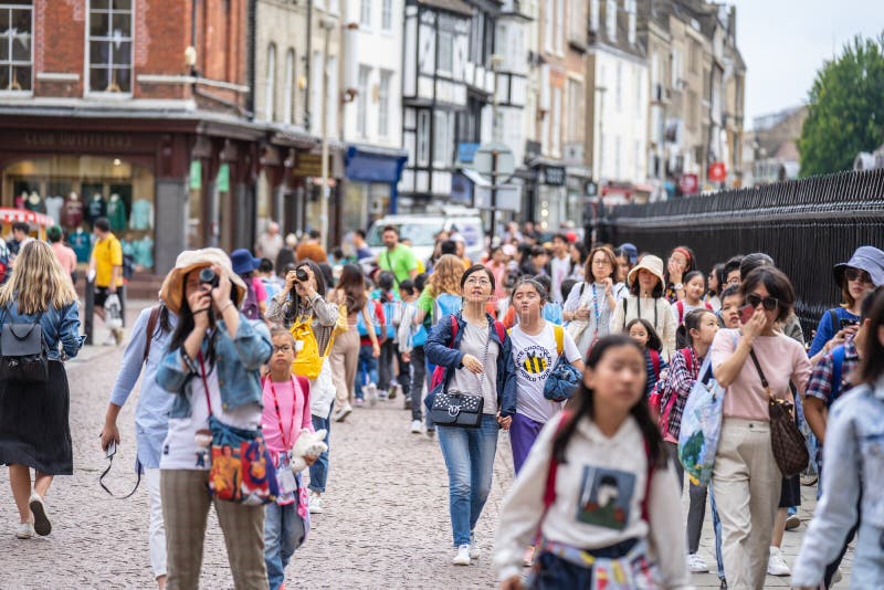 Cambridge, UK, August 1, 2019. Turists walking down and taking pictures at the street of Cambridge on a busy sunny day in front of