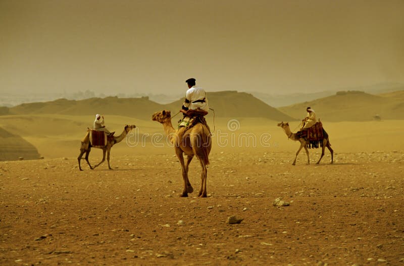 Tři velbloudy a jezdci hlavy směrem k sobě v poušti mimo Cario.