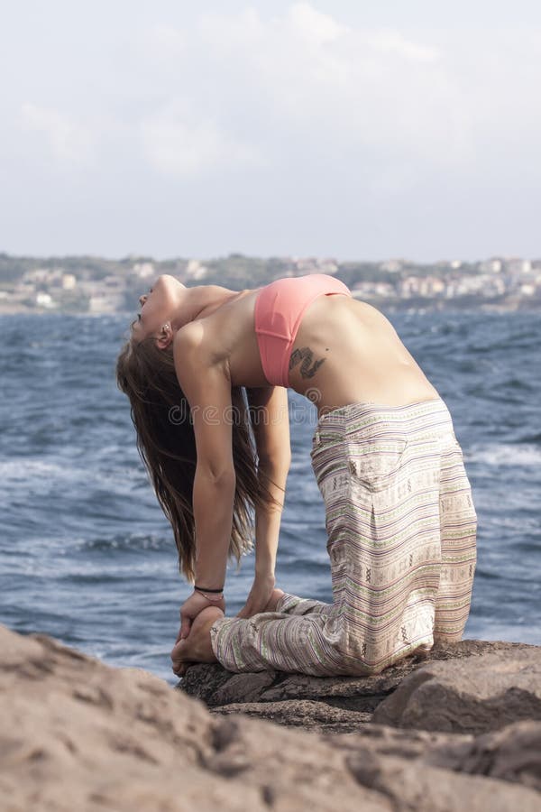 Beautiful girl performing camel pose on the rocks near Sozopol,Bulgaria. Beautiful girl performing camel pose on the rocks near Sozopol,Bulgaria.