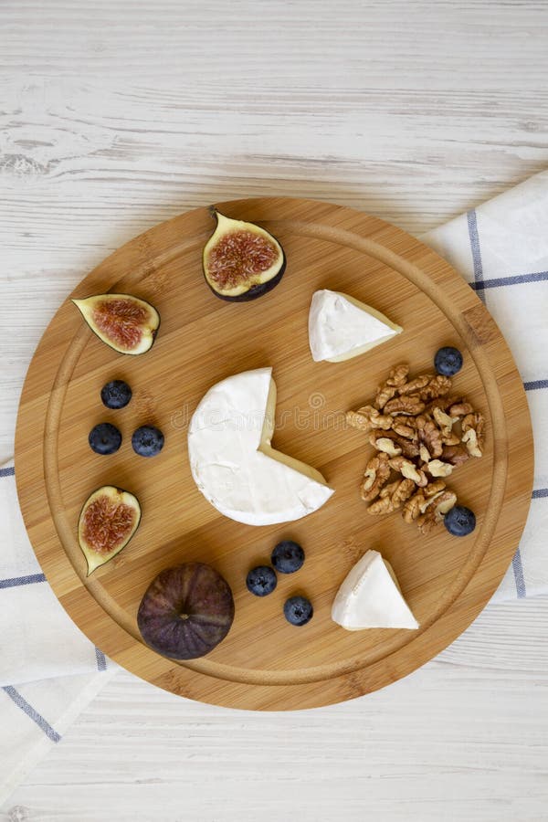Camembert cheese with figs, blueberries and walnuts on a bamboo board over white wooden surface, top view. Food for wine. Close-up royalty free stock photos Camembert cheese with figs, blueberries and walnuts on a bamboo board over white wooden surface, top view. Food for wine. Close-up royalty free stock photos