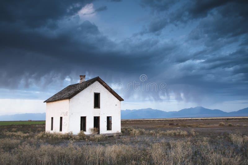 An abandoned house is overcome by a dark and eerie sky. An abandoned house is overcome by a dark and eerie sky