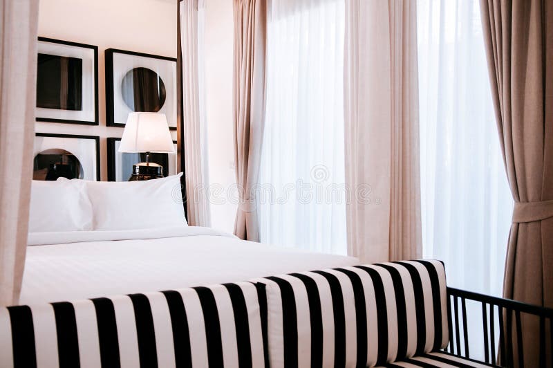 Camera da letto contemporanea asiatica dell'hotel con letto a baldacchino, la tenda bianca, la lampada d'annata e la poltrona in immagine stock Camera da letto contemporanea asiatica dell'hotel con letto a baldacchino, la tenda bianca, la lampada d'annata e la poltrona in immagine stock