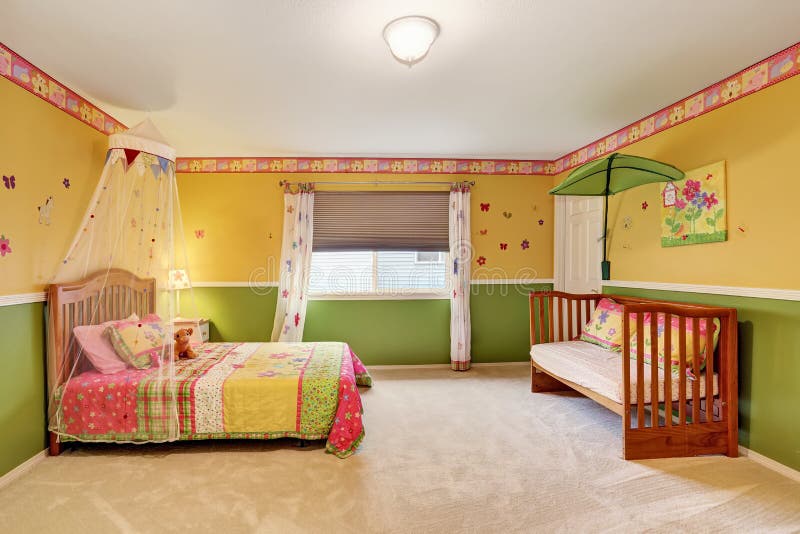 Camera da letto dei bambini nei toni gialli e verdi con il pavimento di tappeto fotografia stock Camera da letto dei bambini nei toni gialli e verdi con il pavimento di tappeto fotografia stock