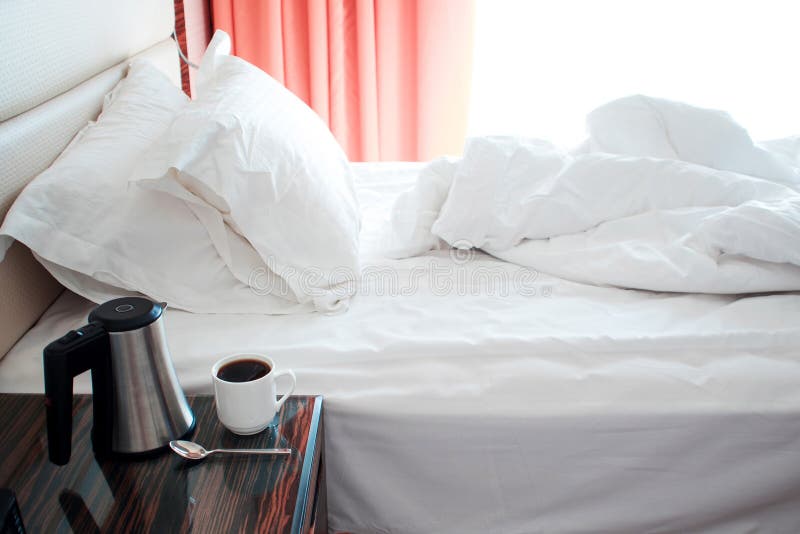 Camera di albergo nella mattina, letto dopo sonno, bollitore e tazza sul comodino immagine stock libera da diritti Camera di albergo nella mattina, letto dopo sonno, bollitore e tazza sul comodino immagine stock libera da diritti