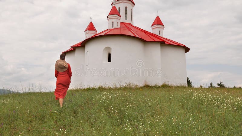 Camera rise to reveal woman walking toward small chapel