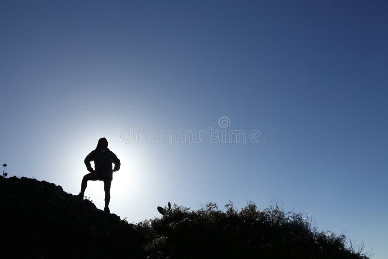 Caminante de la mujer en la silueta que se coloca en la montaña superior fotografía de archivo libre de regalías Caminante de la mujer en la silueta que se coloca en la montaña superior fotografía de archivo libre de regalías