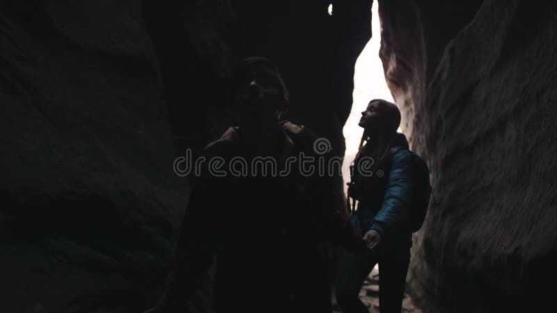 Caminantes jovenes con las mochilas que caminan a través de la cueva oscura, observando el ceil Turismo, tiempo de la aventura Si