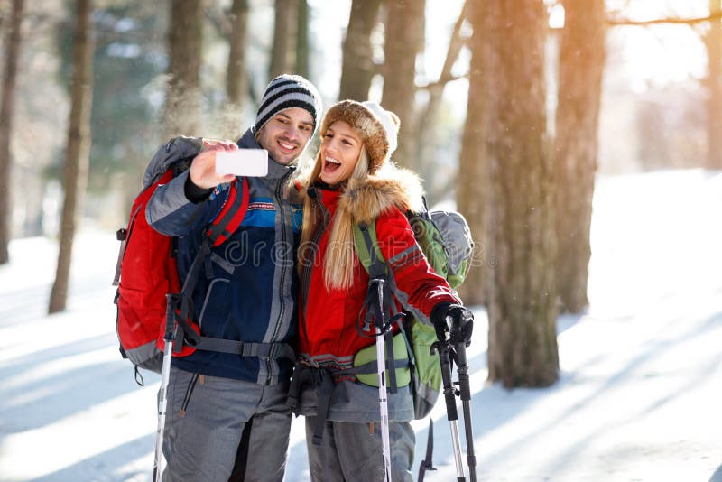 Caminantes masculinos y femeninos que toman las fotos el invierno en madera foto de archivo Caminantes masculinos y femeninos que toman las fotos el invierno en madera foto de archivo
