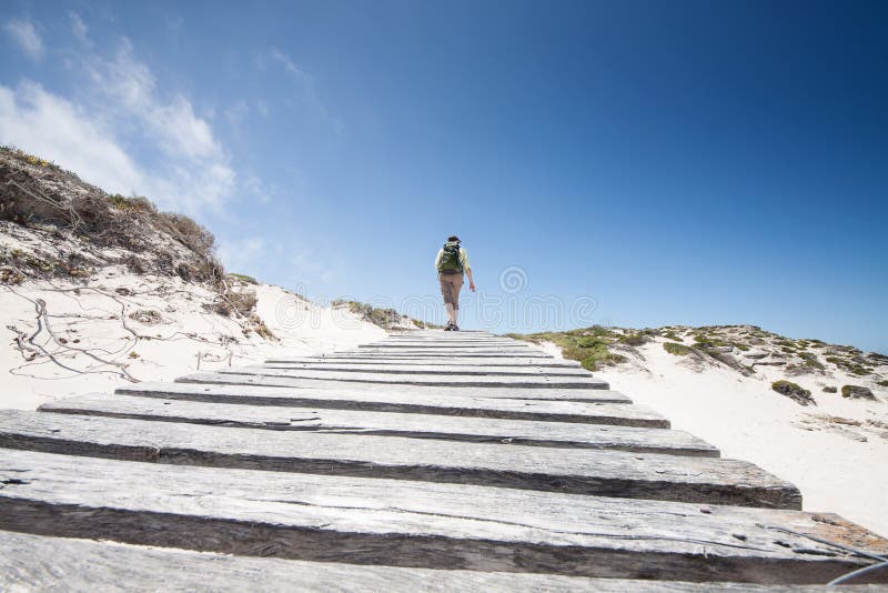 Caminar a la mujer en las dunas de arena blancas en su manera a la playa fotografía de archivo libre de regalías Caminar a la mujer en las dunas de arena blancas en su manera a la playa fotografía de archivo libre de regalías