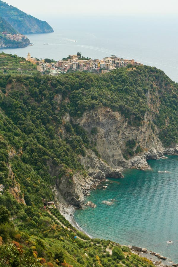 Hiking in the Cinque Terre region along the Ligurian Coast in Northwestern Italy. Seen here from above, the town of Corniglia is perched high above the sea and is one of the five villages that form the famous tourist destination, the 'Cinque Terre.' Manarola, another of the towns is visible in the background. Hiking in the Cinque Terre region along the Ligurian Coast in Northwestern Italy. Seen here from above, the town of Corniglia is perched high above the sea and is one of the five villages that form the famous tourist destination, the 'Cinque Terre.' Manarola, another of the towns is visible in the background.