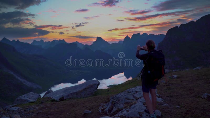 Caminhante atinge o pico da montanha fotografa o pôr do sol