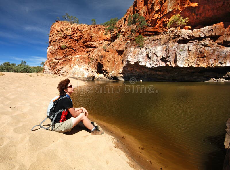 Female hiker seating near Seprentine Gorge waterhole, Western MacDonnell Ranges, Northern Territories, Australia. Female hiker seating near Seprentine Gorge waterhole, Western MacDonnell Ranges, Northern Territories, Australia