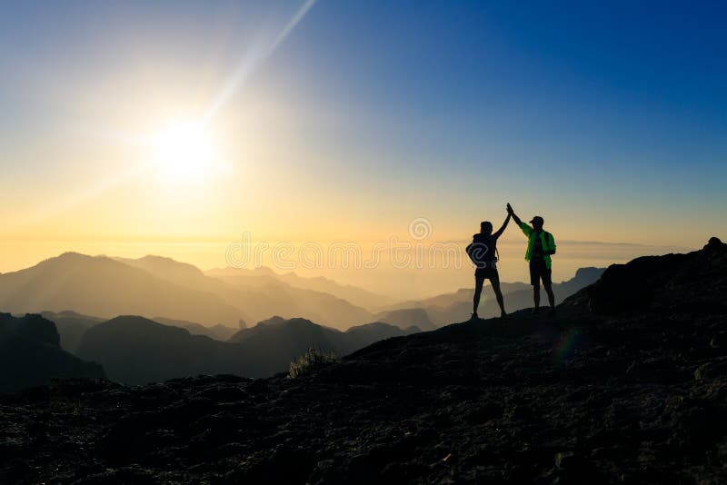 Caminhantes dos pares que comemoram o conceito do sucesso nas montanhas