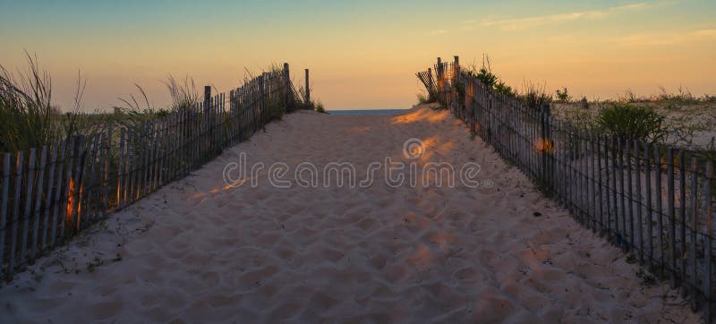 A sandy, fence lined path leads at sunrise to a Delaware beach along the Atlantic Ocean. A sandy, fence lined path leads at sunrise to a Delaware beach along the Atlantic Ocean.