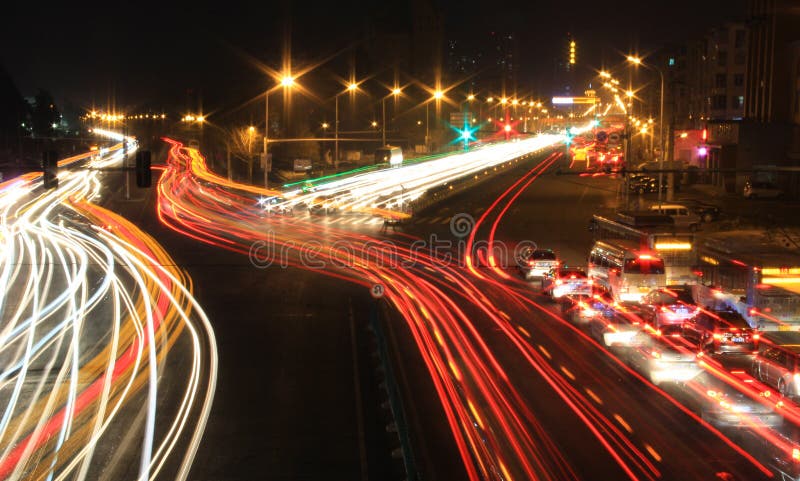 Camino con tráfico de coche en la noche con las luces borrosas