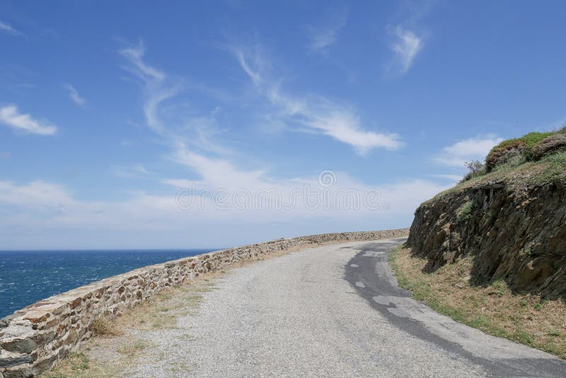Camino costero, camino curvado ascendente con vista al mar y cielo azul nublado fotos de archivo Camino costero, camino curvado ascendente con vista al mar y cielo azul nublado fotos de archivo