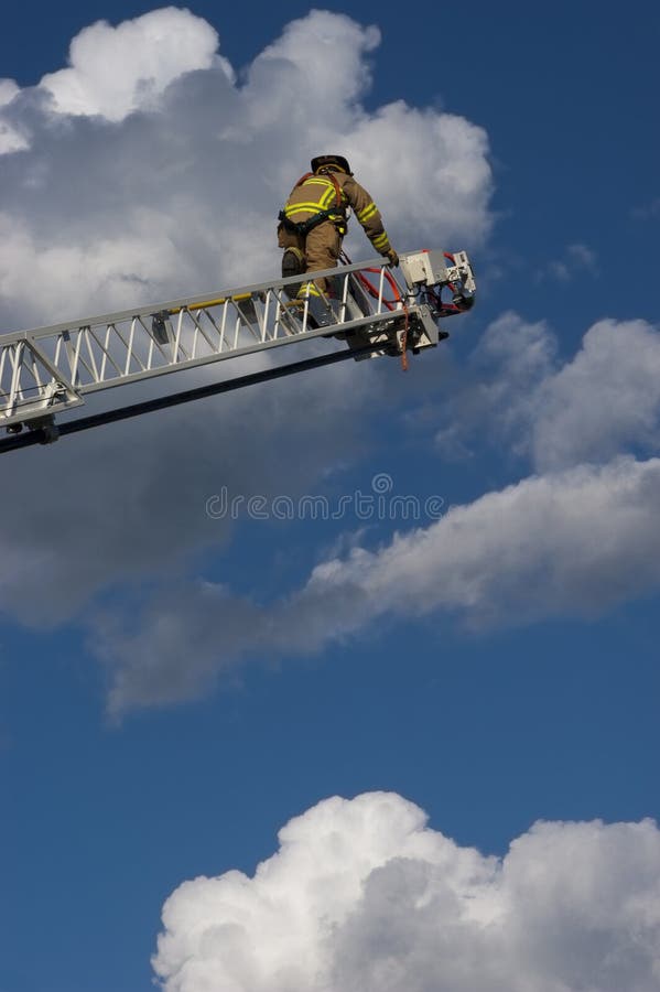 A firemen climbs up a ladder on a firetruck toward the tip where he will use the hose to spray water on a fire. Sky and clouds provide dramatic effect. Many consider first responder and emergency personnel to be a hero. This firefighter is assigned to a ladder company. A firemen climbs up a ladder on a firetruck toward the tip where he will use the hose to spray water on a fire. Sky and clouds provide dramatic effect. Many consider first responder and emergency personnel to be a hero. This firefighter is assigned to a ladder company.