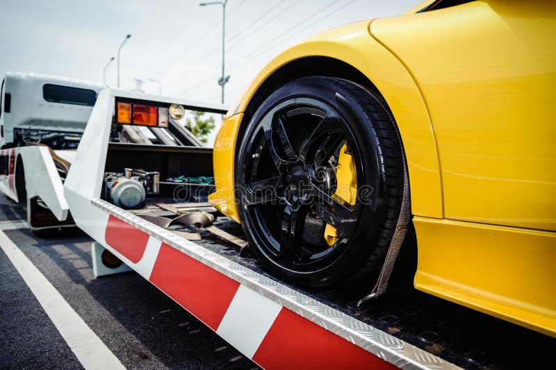 Camion di rimorchio del letto piano che carica un veicolo rotto immagini stock libere da diritti Camion di rimorchio del letto piano che carica un veicolo rotto immagini stock libere da diritti