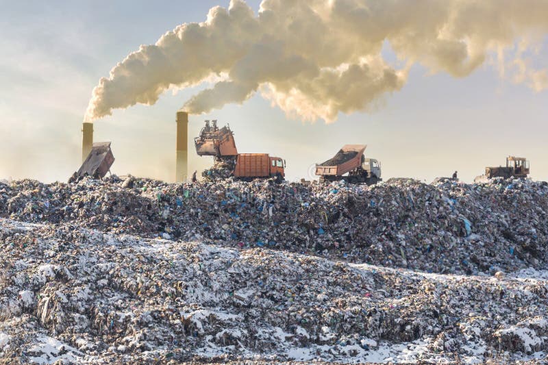 Camiones volquete que descargan la basura sobre el vertido extenso Pilas industriales que fuman en fondo Contaminación ambiental imagen de archivo Camiones volquete que descargan la basura sobre el vertido extenso Pilas industriales que fuman en fondo Contaminación ambiental imagen de archivo