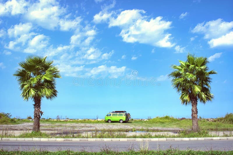 Camionete de campista velha totalmente equipada do temporizador estacionada na Long Beach bonita entre duas palmeiras em um dia d imagem de stock Camionete de campista velha totalmente equipada do temporizador estacionada na Long Beach bonita entre duas palmeiras em um dia d imagem de stock