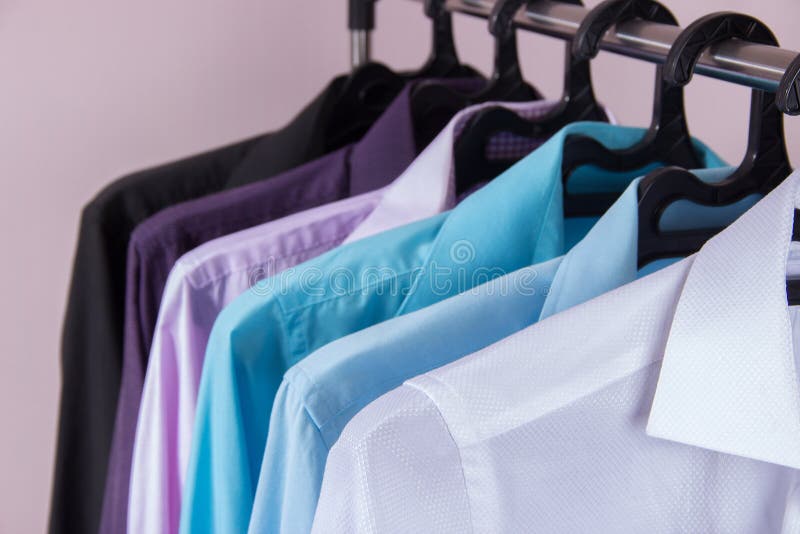 Camisas do ` s dos homens coloridos que penduram em ganchos imagens de stock royalty free Camisas do ` s dos homens coloridos que penduram em ganchos imagens de stock royalty free