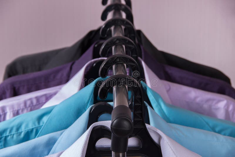 Camisas do ` s dos homens coloridos que penduram em ganchos imagens de stock royalty free Camisas do ` s dos homens coloridos que penduram em ganchos imagens de stock royalty free