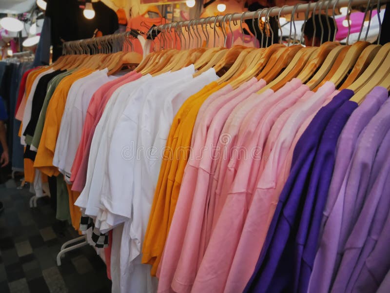 Camisetas coloridas que cuelgan en el estante en la tienda al por menor fotografía de archivo Camisetas coloridas que cuelgan en el estante en la tienda al por menor fotografía de archivo