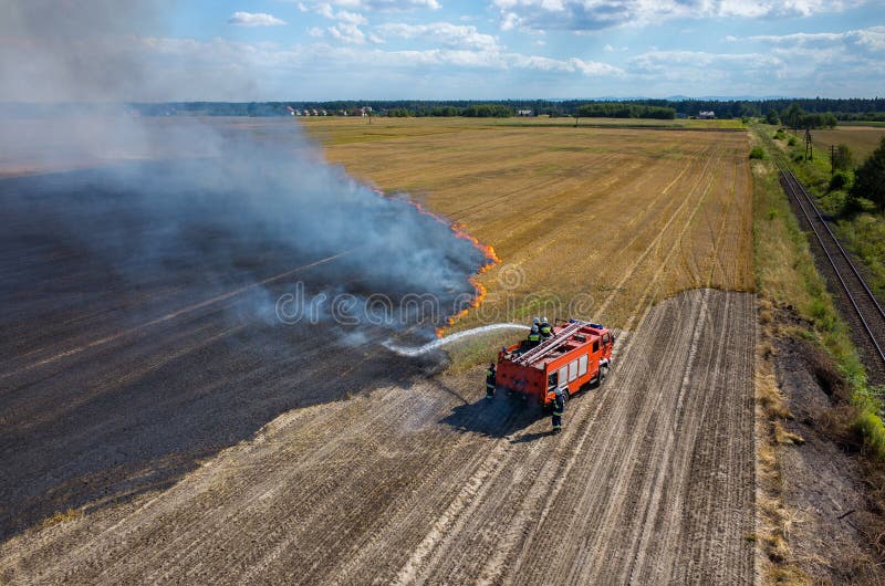 Camión del bombero que trabaja en el campo en el fuego foto de archivo libre de regalías Camión del bombero que trabaja en el campo en el fuego foto de archivo libre de regalías