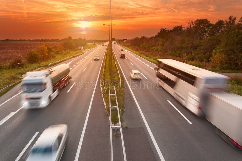 Camión y autobús en la autopista en la puesta del sol foto de archivo libre de regalías Camión y autobús en la autopista en la puesta del sol foto de archivo libre de regalías