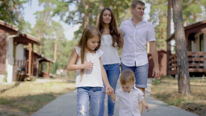 Camminata maschio e femminile felice con i bambini fuori