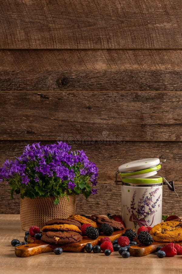 Campanula viola e barattolo ceramico con i biscotti e le bacche selvatiche su fondo di legno scuro immagine stock libera da diritti Campanula viola e barattolo ceramico con i biscotti e le bacche selvatiche su fondo di legno scuro immagine stock libera da diritti