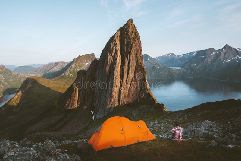 Camping in Norway man traveler relaxing in mountains with tent. Travel adventure healthy lifestyle active summer vacations sunset Segla mountain peak view stock photography Camping in Norway man traveler relaxing in mountains with tent. Travel adventure healthy lifestyle active summer vacations sunset Segla mountain peak view stock photography