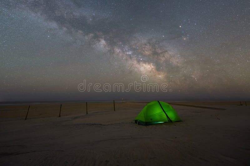 Milky Way Galaxy rising behind a lit tent at Assateague Island National Seashore in Maryland. Milky Way Galaxy rising behind a lit tent at Assateague Island National Seashore in Maryland