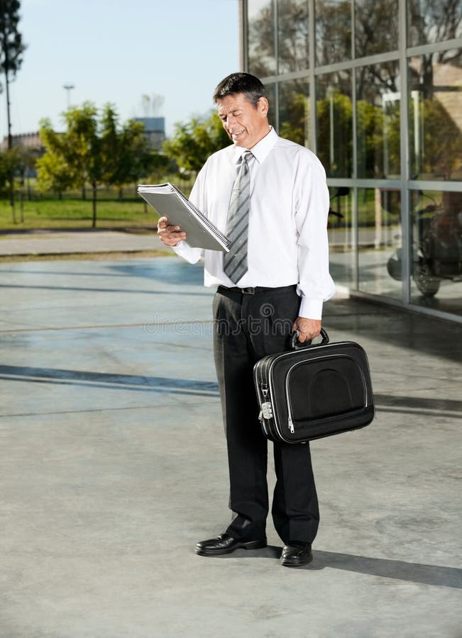Campus universitaire masculin de professeur Reading Book At photographie stock