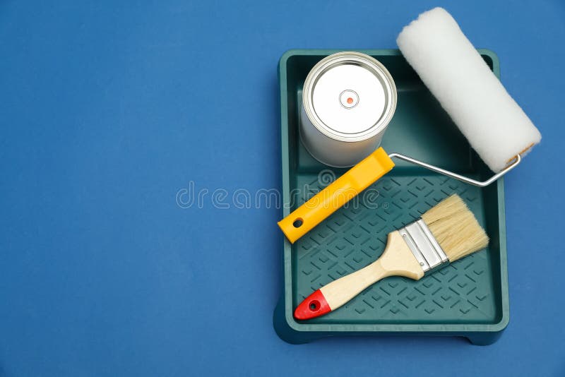 Can of Orange Paint, Brush, Roller and Container on Blue Background