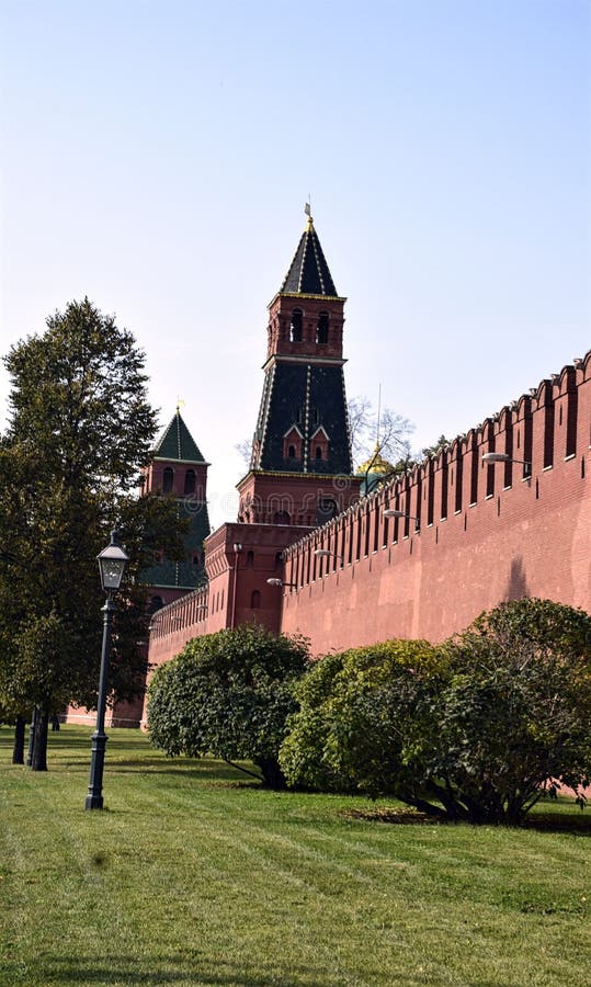 We can see kremlin wall with towers ander the sunny weather with grass field and trees. We can see kremlin wall with towers ander the sunny weather with grass field and trees