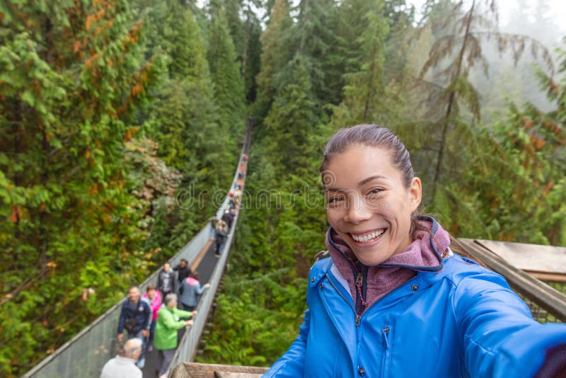 Canada travel tourist woman taking selfie photo at Capilano Suspension Bridge in Vancouver, British Columbia.