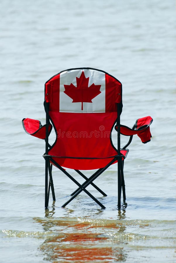 Folding chair with canadian flag design in shallow lake water. Folding chair with canadian flag design in shallow lake water