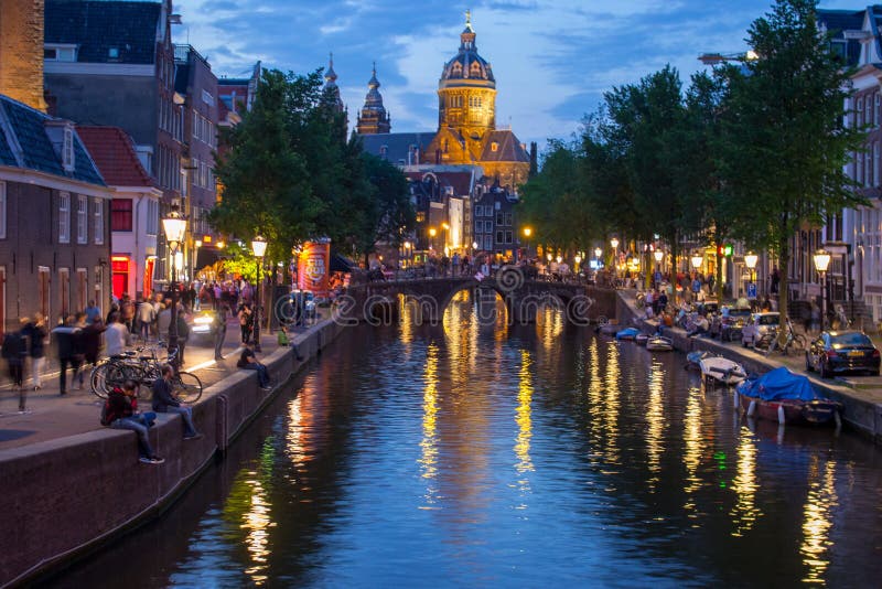 Canal with bridge, cathedral and boats in evening Amsterdam. Traditional dutch cityscape in twilight. stock photo Canal with bridge, cathedral and boats in evening Amsterdam. Traditional dutch cityscape in twilight. stock photo