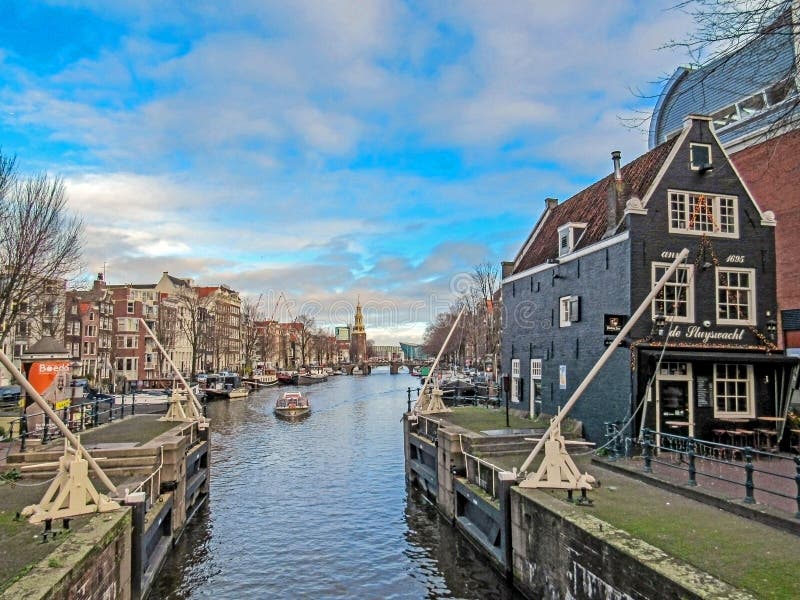 Canal de ville à Amsterdam avec des bateaux et des maisons de brique se reflétant dans l'eau photo stock Canal de ville à Amsterdam avec des bateaux et des maisons de brique se reflétant dans l'eau photo stock