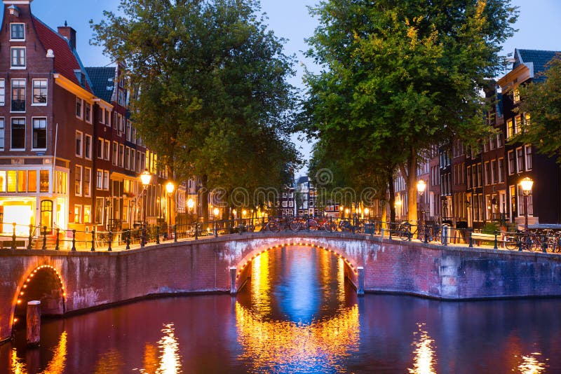 Canales de Amsterdam en la puesta del sol con las luces