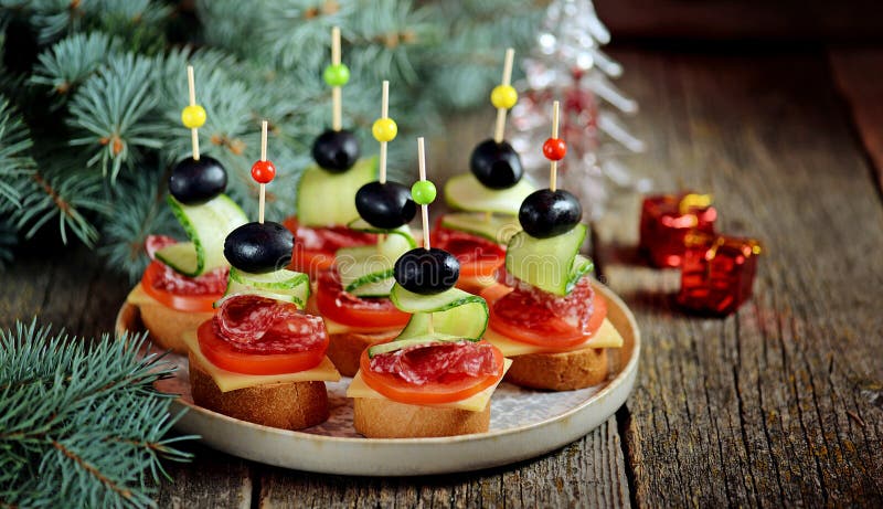 Canape do Natal no espeto do baguette do pão com queijo, salsicha, tomate, pepino e azeitonas do brinde Petisco tradicional para imagem de stock royalty free Canape do Natal no espeto do baguette do pão com queijo, salsicha, tomate, pepino e azeitonas do brinde Petisco tradicional para imagem de stock royalty free