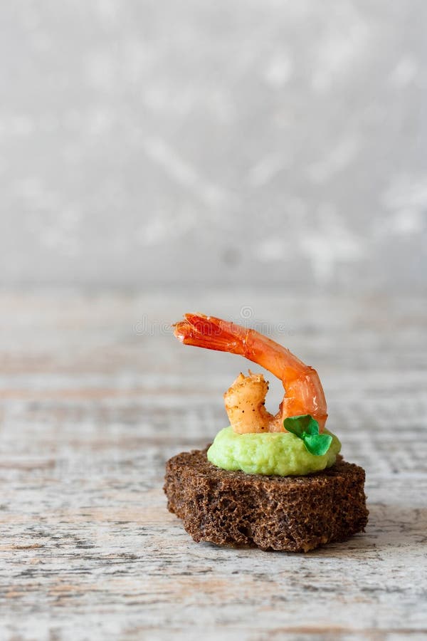 Canapes with avocado muslim and garlic shrimp on brown bread. Simple and easy snack for parties and banquets. Comfortable food. Canapes with avocado muslim and garlic shrimp on brown bread. Simple and easy snack for parties and banquets. Comfortable food