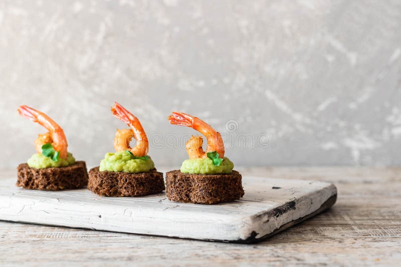 Canapes with avocado muslim and garlic shrimp on brown bread. Simple and easy snack for parties and banquets. Comfortable food. Canapes with avocado muslim and garlic shrimp on brown bread. Simple and easy snack for parties and banquets. Comfortable food