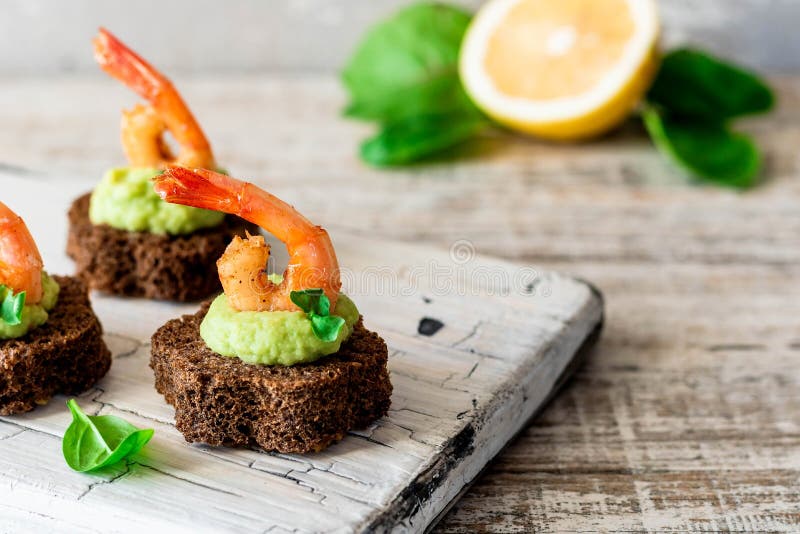 Canapes with avocado muslim and garlic shrimp on brown bread. Simple and easy snack for parties and banquets. Comfortable food. Canapes with avocado muslim and garlic shrimp on brown bread. Simple and easy snack for parties and banquets. Comfortable food