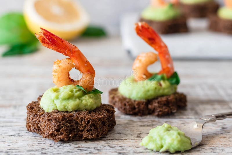 Canapes with avocado muslim and garlic shrimp on brown bread. Simple and easy snack for parties and banquets. Comfortable food. Canapes with avocado muslim and garlic shrimp on brown bread. Simple and easy snack for parties and banquets. Comfortable food