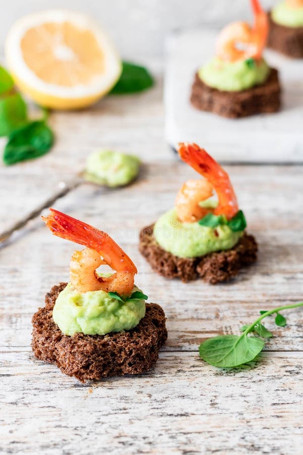 Canapes with avocado muslim and garlic shrimp on brown bread. Simple and easy snack for parties and banquets. Comfortable food. Canapes with avocado muslim and garlic shrimp on brown bread. Simple and easy snack for parties and banquets. Comfortable food