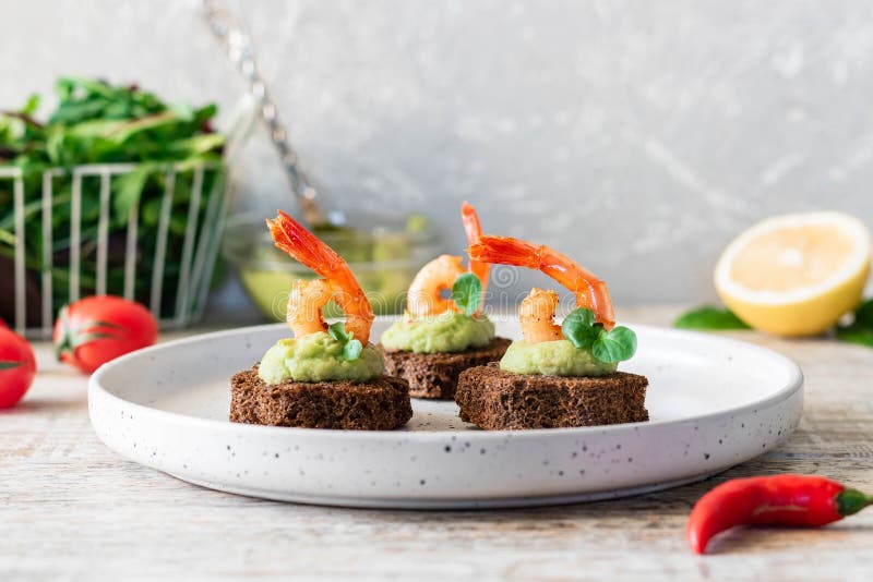 Canapes with avocado muslim and garlic shrimp on brown bread. Simple and easy snack for parties and banquets. Comfortable food. Canapes with avocado muslim and garlic shrimp on brown bread. Simple and easy snack for parties and banquets. Comfortable food